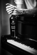 Planat Cognac Over Proof 65% — bouteille sur piano, noir et blanc, photographie Antoine Ollier