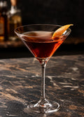 Hee Joy Spiced Rum, cocktail servi en verre à cocktail avec zeste d'orange